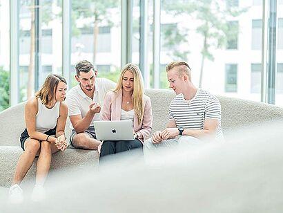 Auf dem Foto sind vier Studierende zu sehen, die gemeinsam auf einen Laptop schauen.