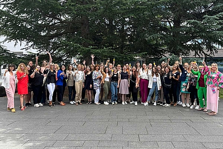 Alle Teilnehmerinnen des Programms versammeln sich auf dem Hof vor dem Gebäude der DHBW Heilbronn vor einem Baum und winken ins Bild. 