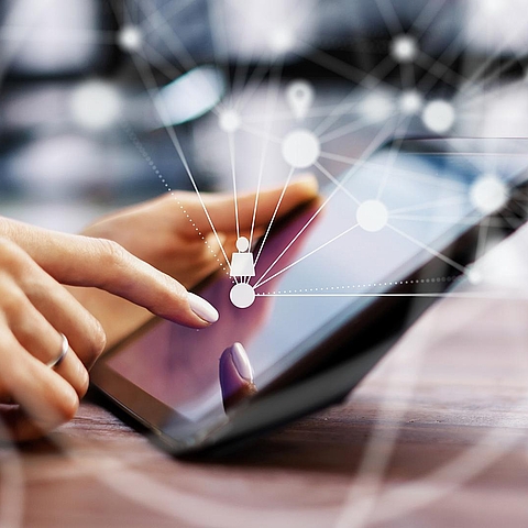 Auf dem Bild ist ein Tablet zu sehen. Außerdem sind einige Punkte dargestellt, die mit Strichen verbunden sind, um eine Vernetzung darzustellen.