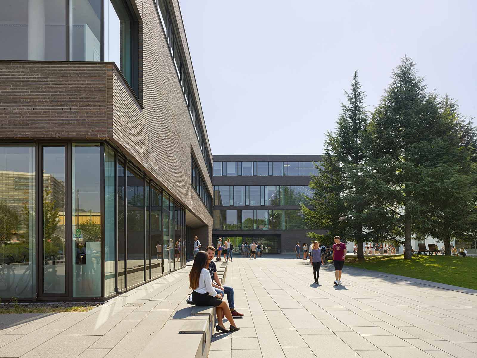 Studenten sitzen vor den DHBW-Gebäuden auf dem Bildungscampus Nord.