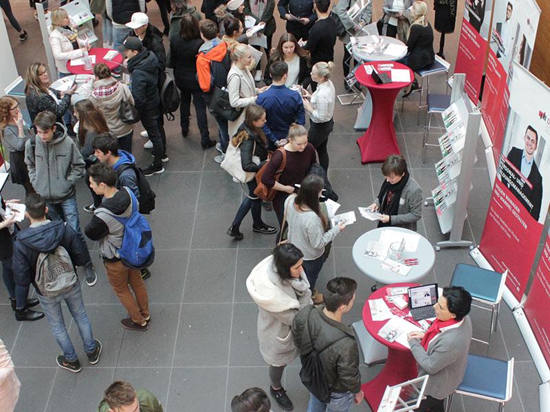 Das Foto zeigt viele Menschen und Informationsstände der DHBW auf dem Studieninformationstag. Das Bild ist aus der Vogelperspektive aufgenommen.