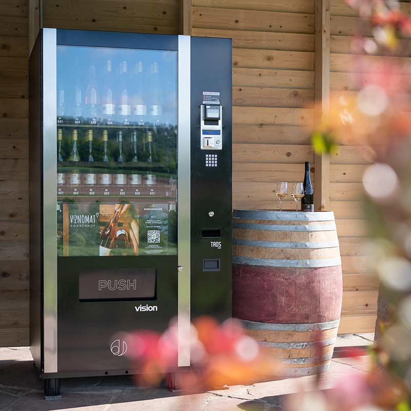 Weinautomat und Weinfass vor einer Holzwand