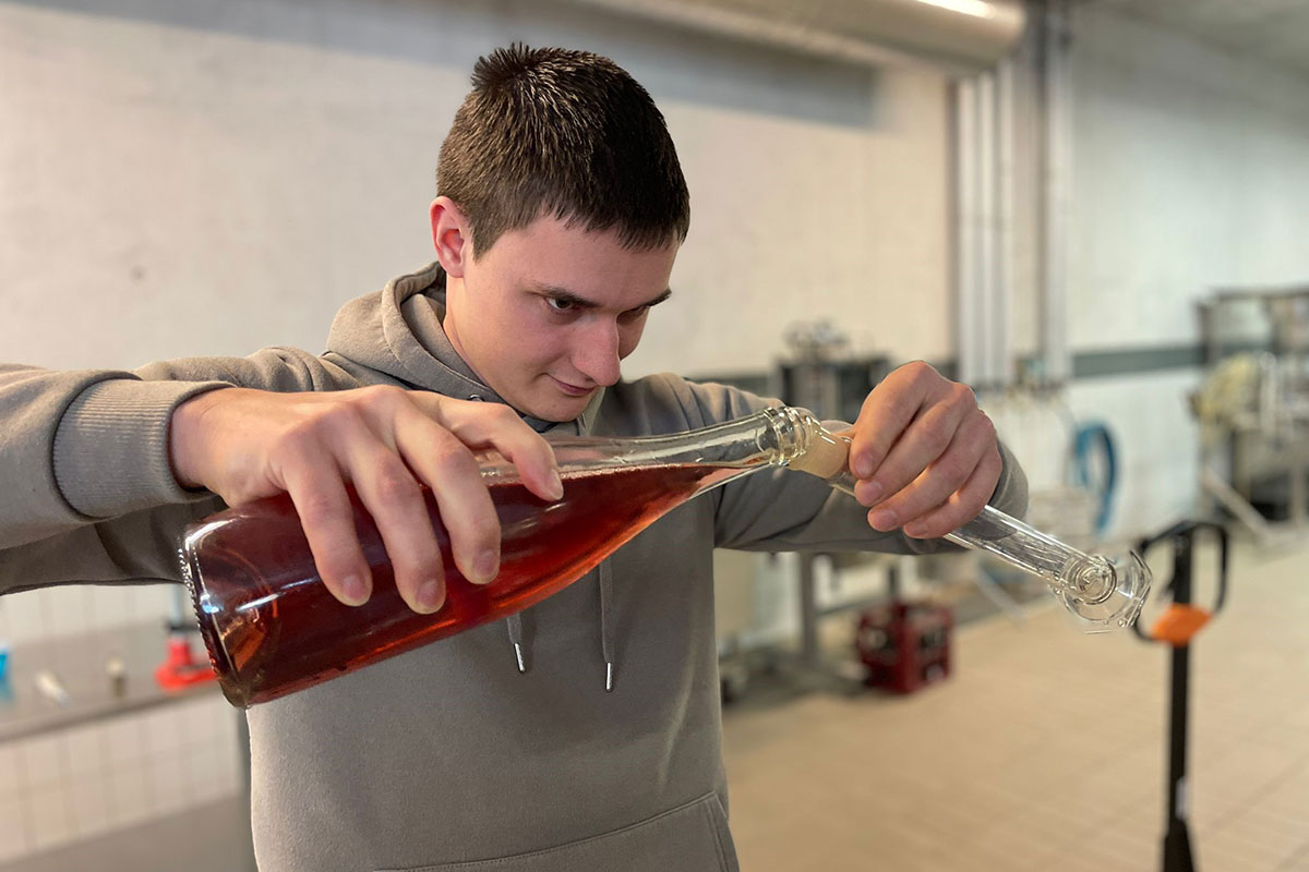 Student schenkt Sekt in ein Glas ein