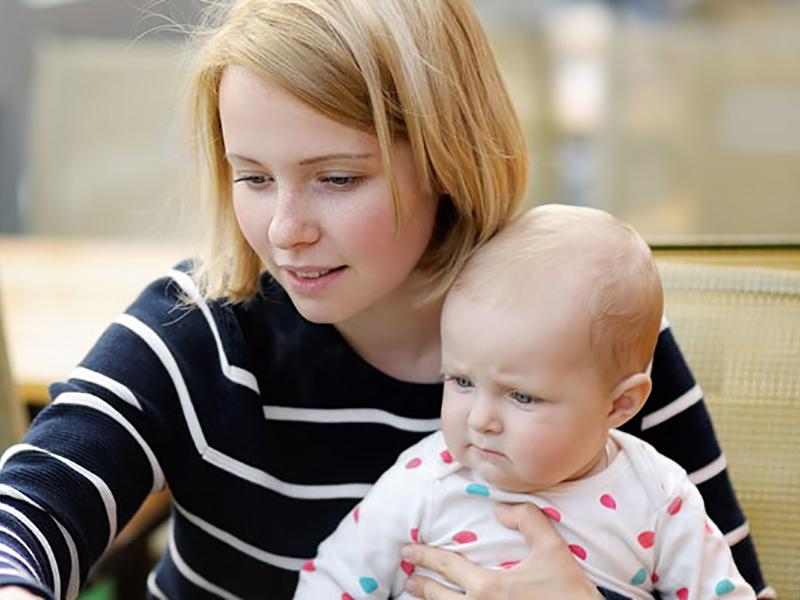 Das Foto zeigt eine Frau, die ein Baby hält.