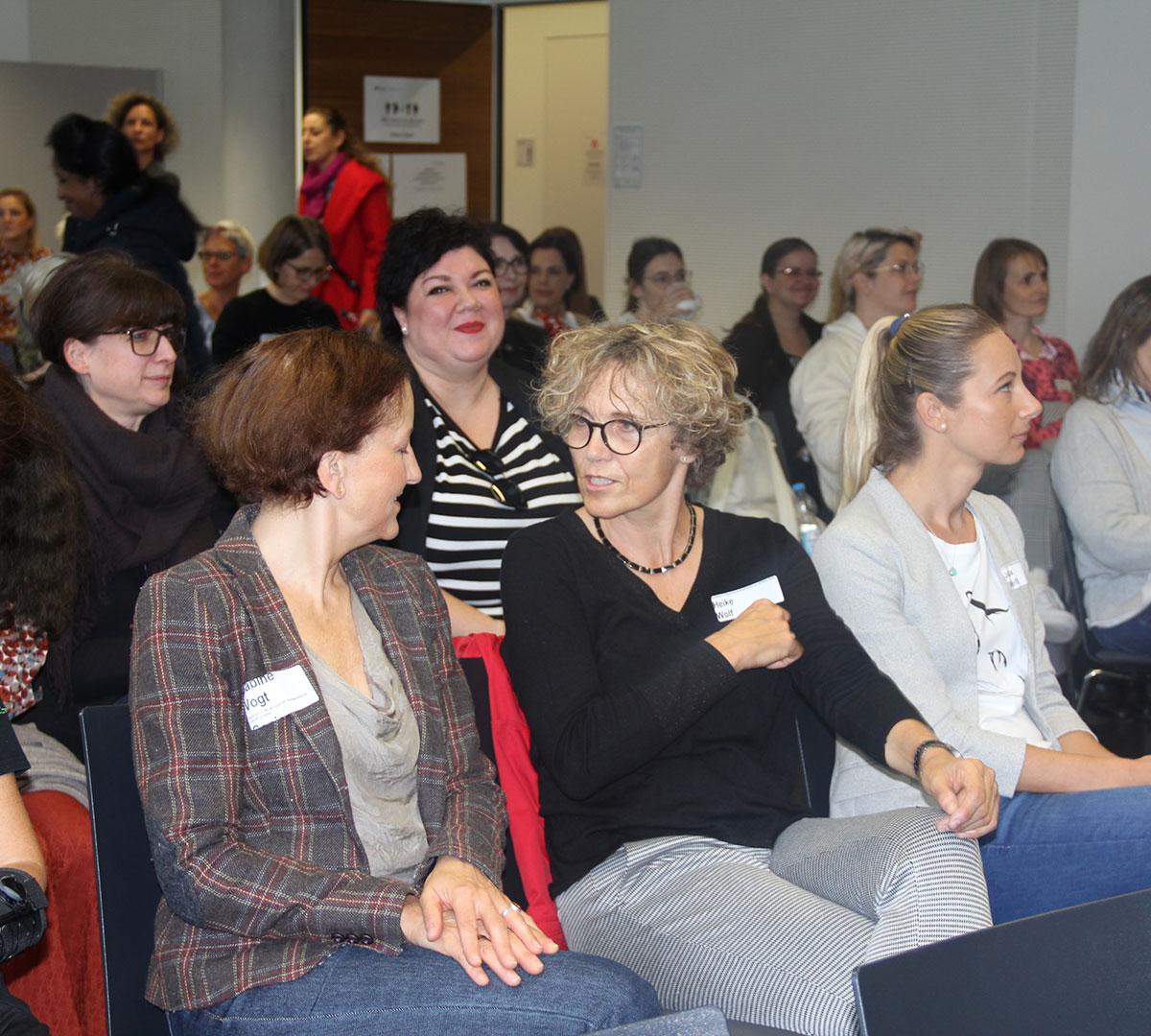 Zuhörerinnen sitzen im Saal und warten auf die Eröffnung. 