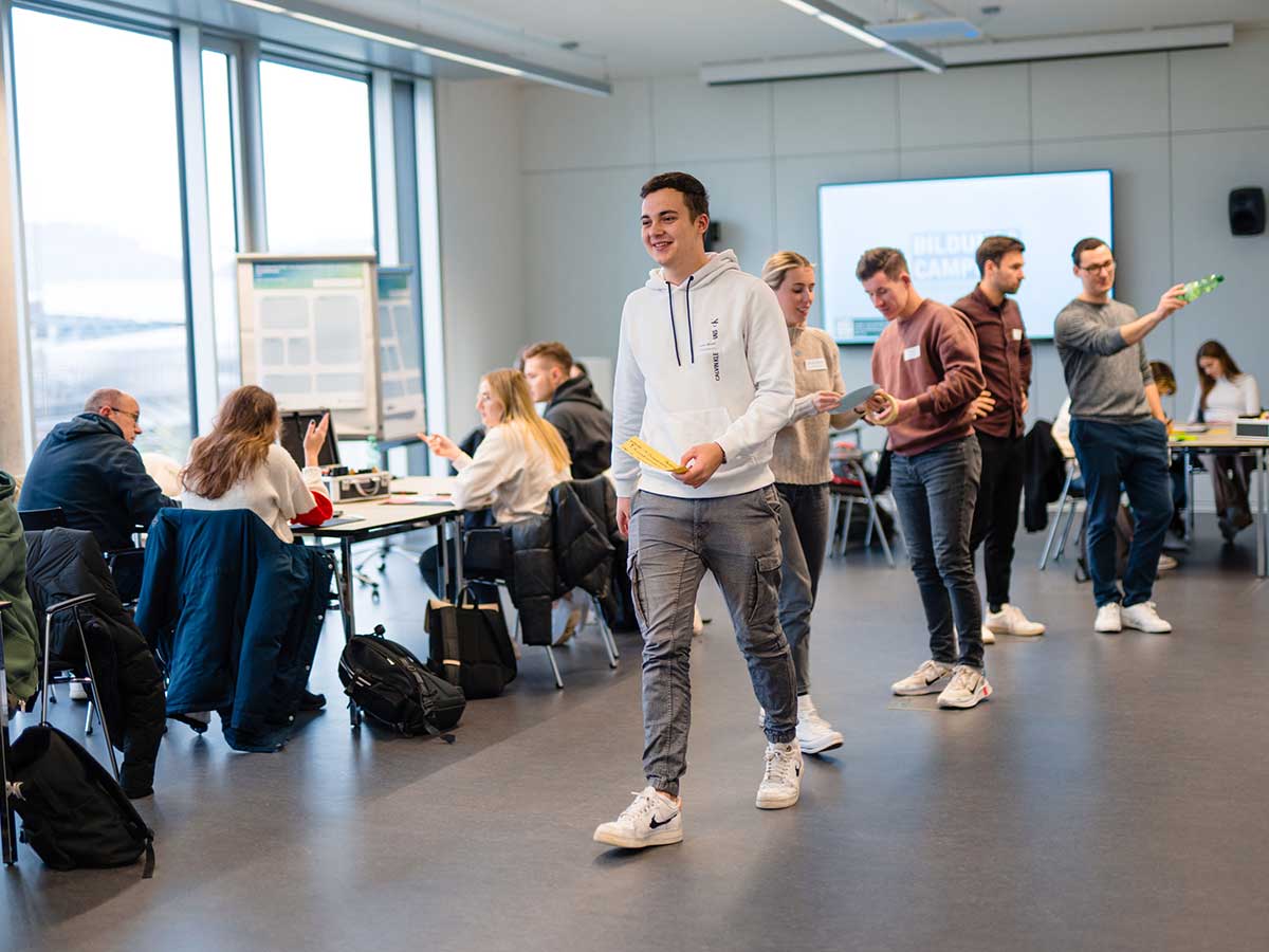 Studierende verteilen sich an den Tischen im Raum. 