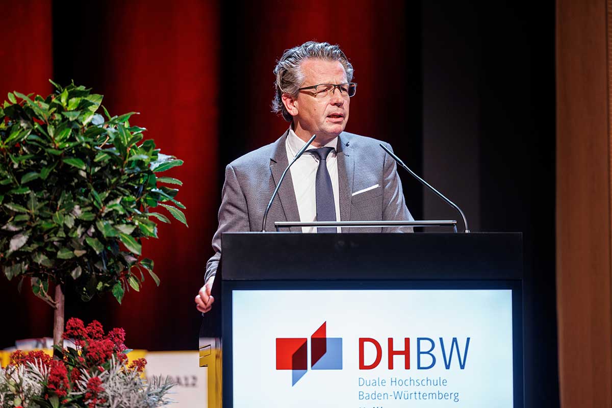 Doktor Dieter Blankenhorn, Leiter der Staatlichen Lehr- und Versuchsanstalt für Wein- und Obstbau in Weinsberg, steht am Rednerpult, trägt einen grauen Anzug und Brille. 