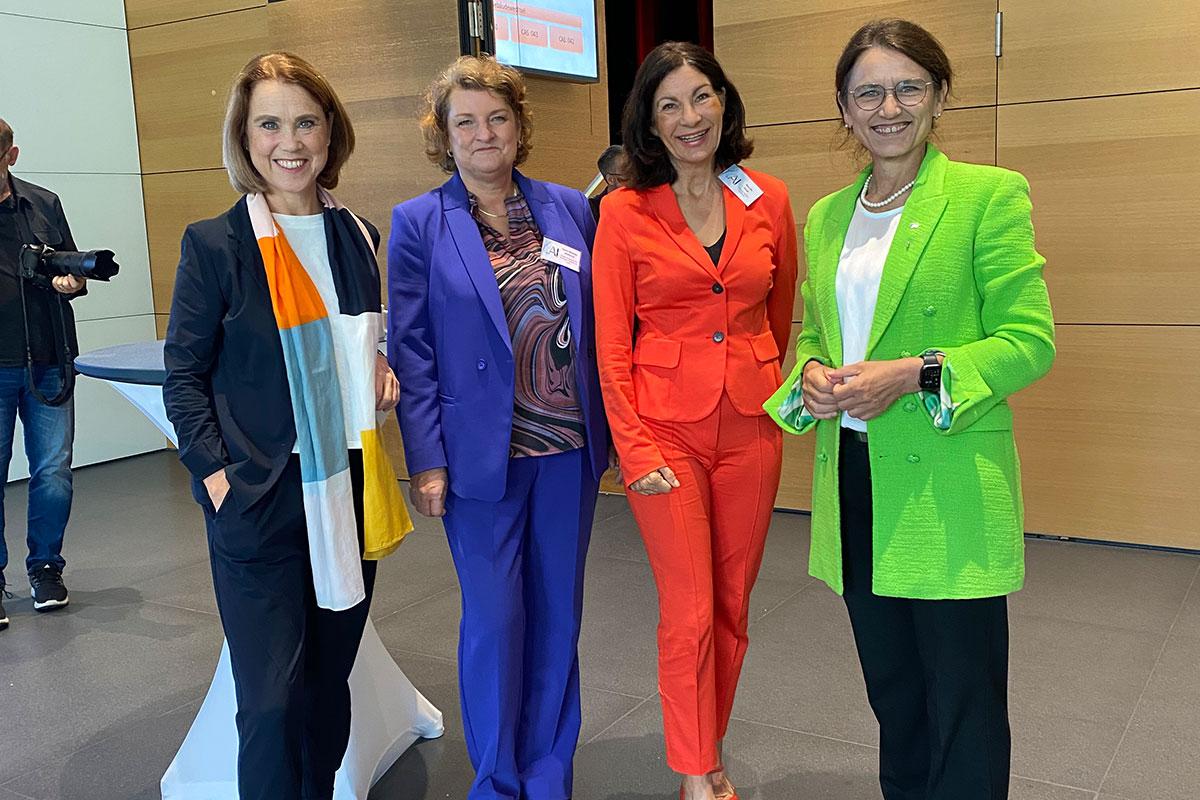 Vier Frauen stehen im Foyer der Aula für ein Gruppenfoto: Die Ministerin Petra Olschowski in einem dunkelblauen Anzug mit Turnschuhen, Vizepräsidentin der DHBW Doris Nitsche-Ruhland in einem royalblauen Anzug, die Rektorin der DHBW Heilbronn, Prof. Dr. Nicole Graf, in einem orange-rotem Business-Anzug und die Präsidentin der DHBW, Prof. Dr. Martina Klärle, in neongrünem Blazer mit schwarzer Hose. 