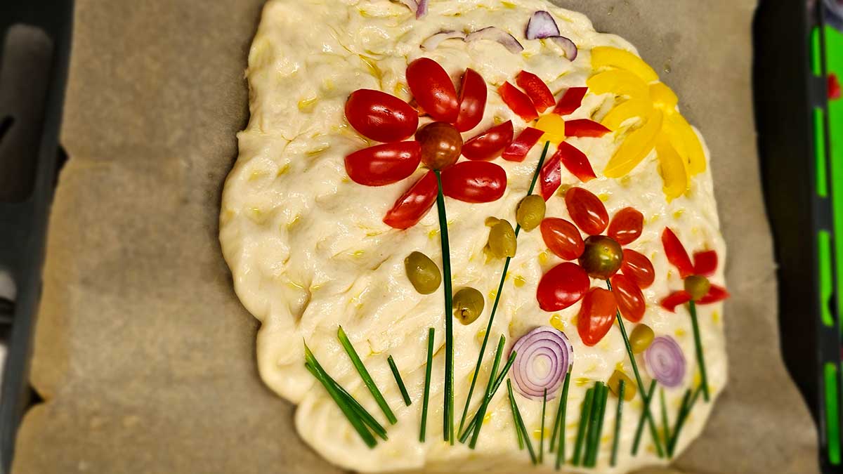 Das Ergebnis des Backwokshops: Eine Garten-Foccacia. Das Gemüse auf der Foccacia ist so gelegt, dass es aussieht wie eine bunte Blumenwiese.