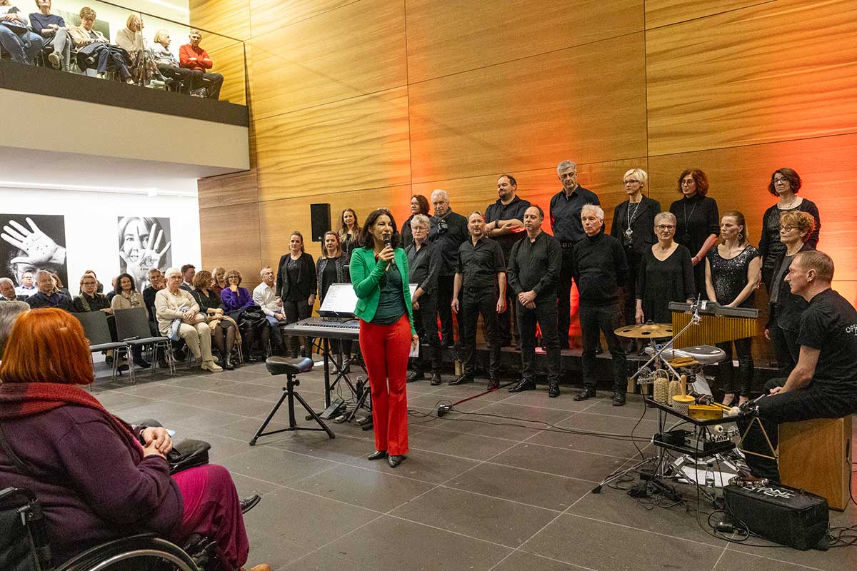 Mit ihrer Begrüßung stimmte Prof. Dr. Nicole Graf ein den Abend voller Musik ein. Nicole Graf ist in den Weihnachtsfarben gekleidet - rote Hose und grüne Bluse - und trägt eine Kette aus Weihnachtskugeln. 