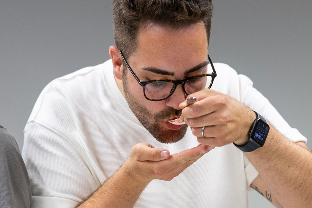 Teilnehmer beim Kaffee-Aromenworkshop schlürft sich nach der Cupping-Methode löffelweise durch verschiedene Kaffeesorten 