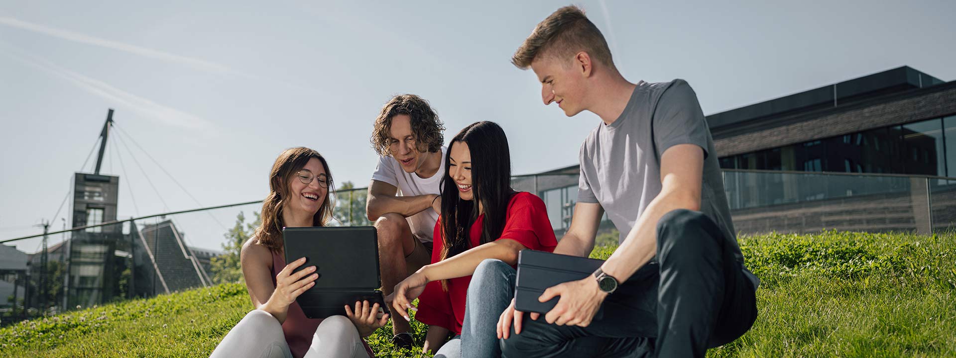 Studierende auf dem Mensahügel auf dem Bildungscampus, die sich etwas am Laptop anschauen